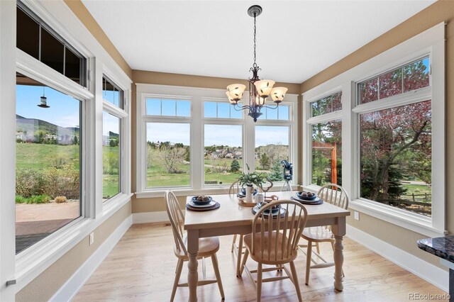 sunroom / solarium with baseboards, a notable chandelier, and wood finished floors