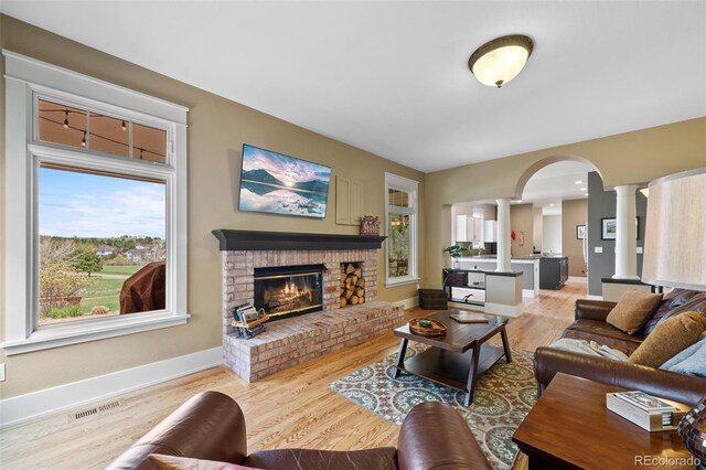 living room with ornate columns, arched walkways, baseboards, and visible vents