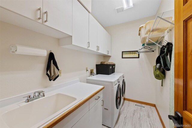 laundry area with a sink, visible vents, cabinet space, and washer and clothes dryer