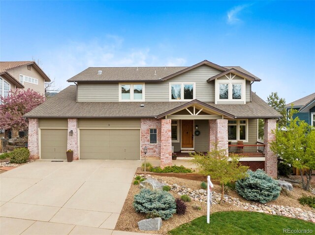 craftsman inspired home featuring concrete driveway, brick siding, a porch, and roof with shingles