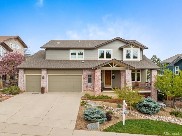 craftsman house with roof with shingles, a porch, driveway, and brick siding