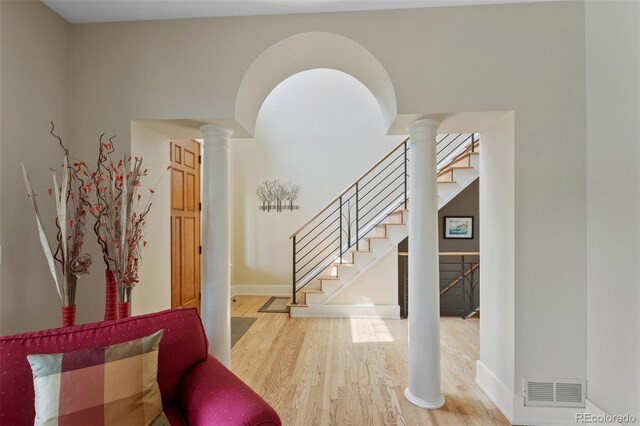 foyer with visible vents, wood finished floors, stairway, baseboards, and ornate columns