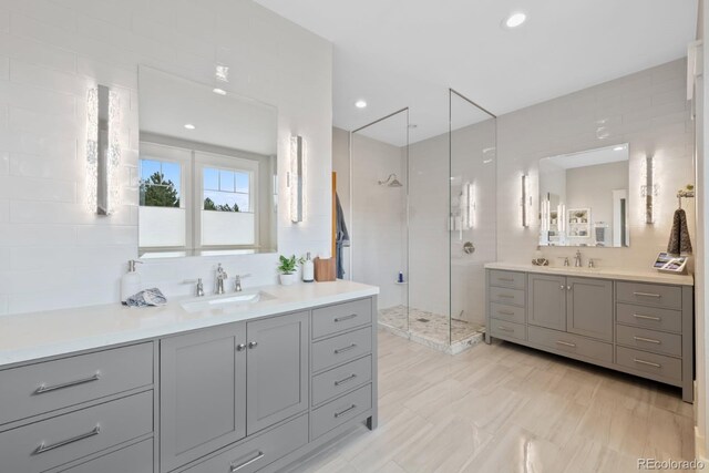 bathroom with a sink, a shower stall, and two vanities