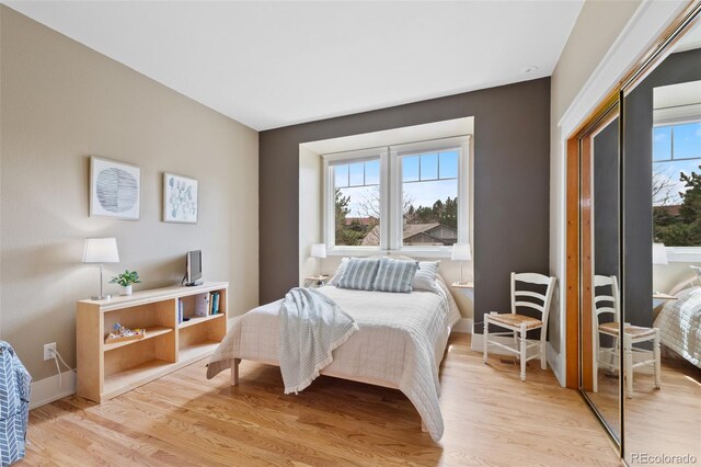 bedroom with baseboards, multiple windows, and light wood-style flooring