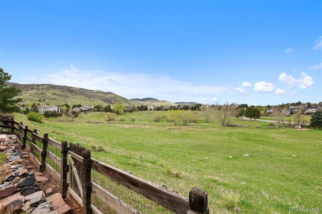 view of yard with a mountain view, fence, and a rural view