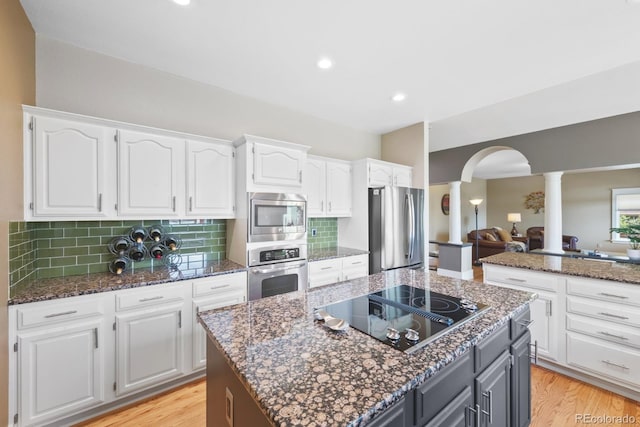 kitchen with ornate columns, arched walkways, appliances with stainless steel finishes, and white cabinetry