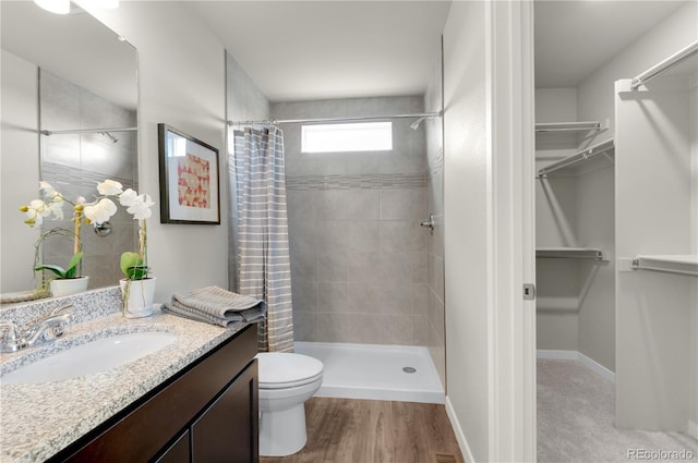 46534 Avery Ln, Bennett, CO 80102 - full bathroom with a tile shower, a spacious closet, vanity, toilet, and wood finished floors