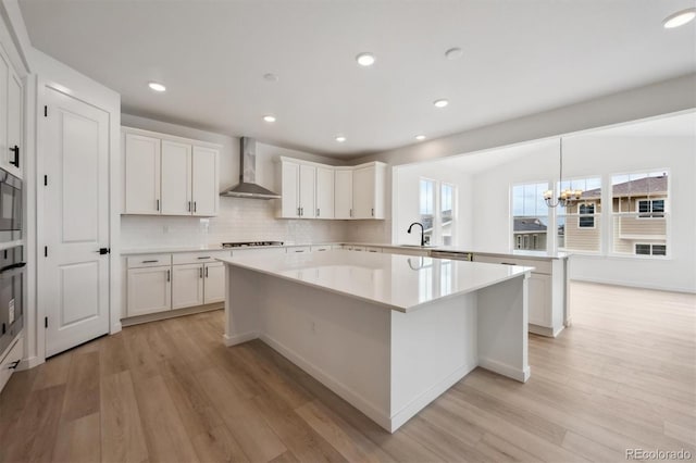 24768 E 40th Ave, Aurora, CO 80019 - kitchen with wall chimney exhaust hood, a peninsula, light wood-type flooring, appliances with stainless steel finishes, and recessed lighting
