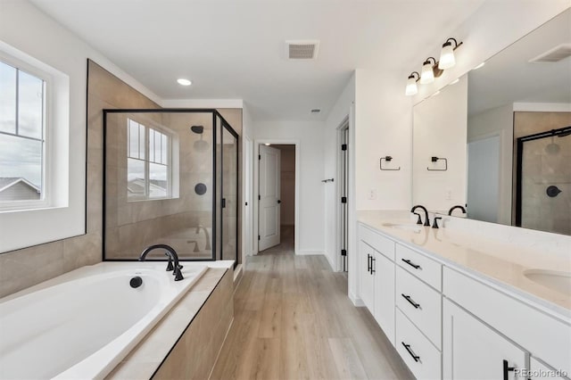 24768 E 40th Ave, Aurora, CO 80019 - bathroom featuring a shower stall, a bath, double vanity, wood finished floors, and recessed lighting