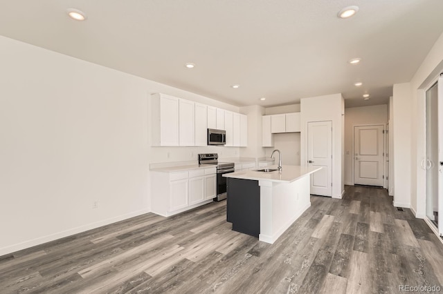 kitchen featuring hardwood / wood-style floors, a center island with sink, white cabinets, sink, and appliances with stainless steel finishes