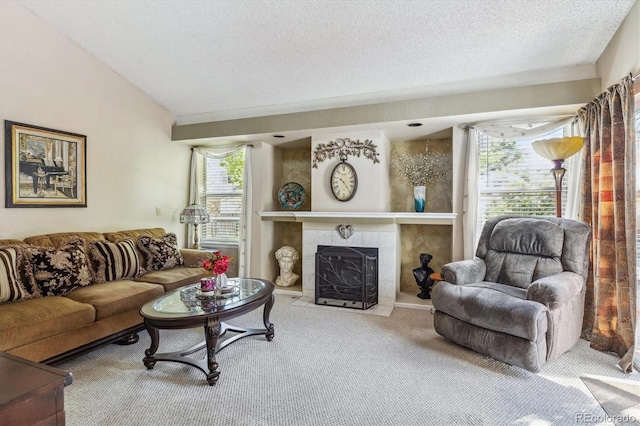 living room with carpet floors, a textured ceiling, and a tiled fireplace