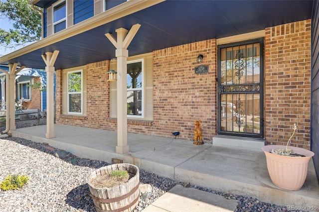 doorway to property with brick siding and a porch