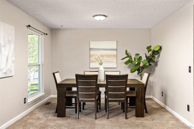 dining space with carpet floors, a textured ceiling, and baseboards
