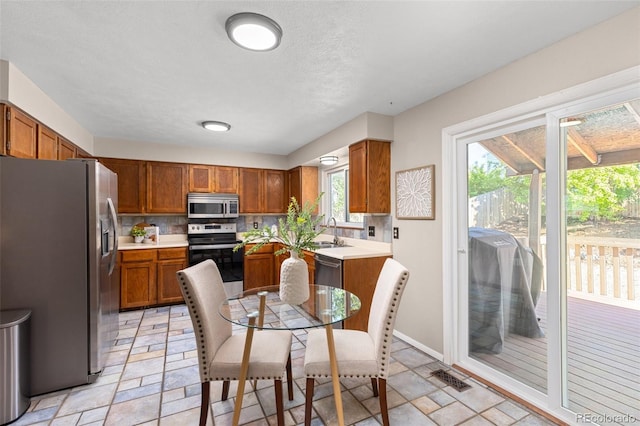 kitchen with appliances with stainless steel finishes, a sink, brown cabinets, and backsplash