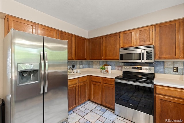 kitchen with stainless steel appliances, light countertops, backsplash, and brown cabinetry