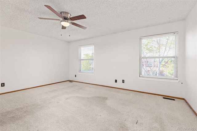 carpeted spare room featuring a textured ceiling, baseboards, and ceiling fan