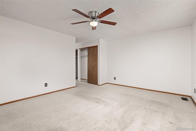 unfurnished bedroom with light colored carpet, baseboards, a closet, a ceiling fan, and a textured ceiling