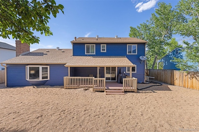 back of property with a fenced backyard, a wooden deck, and a shingled roof