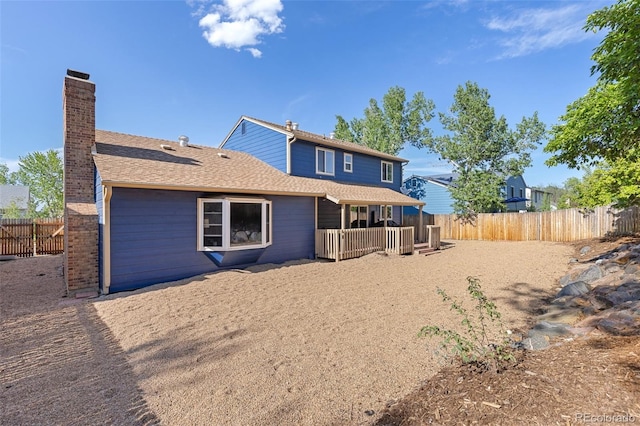 back of property with a chimney, a fenced backyard, and roof with shingles