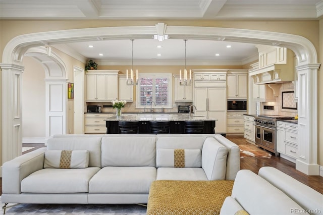 living room with beamed ceiling, dark hardwood / wood-style floors, an inviting chandelier, and crown molding