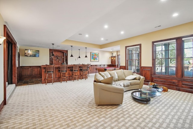 carpeted living room featuring wooden walls and indoor bar