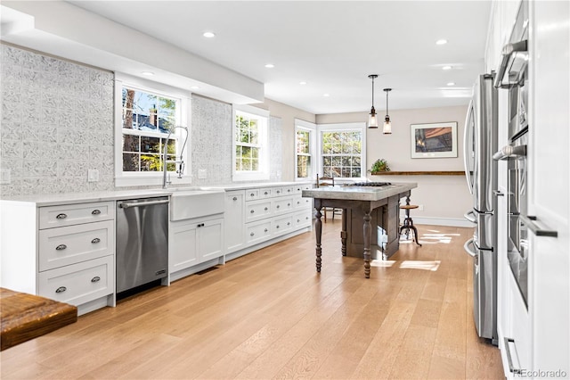 kitchen with light hardwood / wood-style flooring, dishwasher, white cabinets, pendant lighting, and backsplash