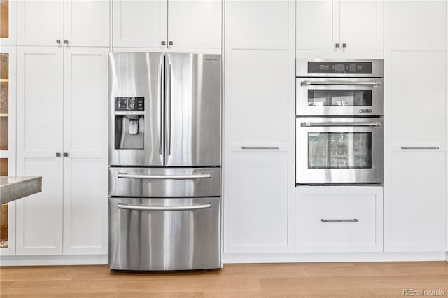 kitchen with light hardwood / wood-style flooring, white cabinets, and appliances with stainless steel finishes