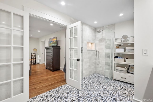 bathroom featuring wood-type flooring, french doors, and tiled shower