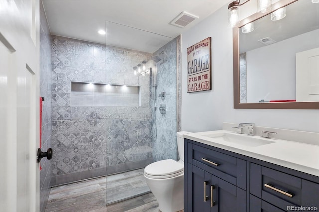 bathroom with vanity, toilet, and tiled shower