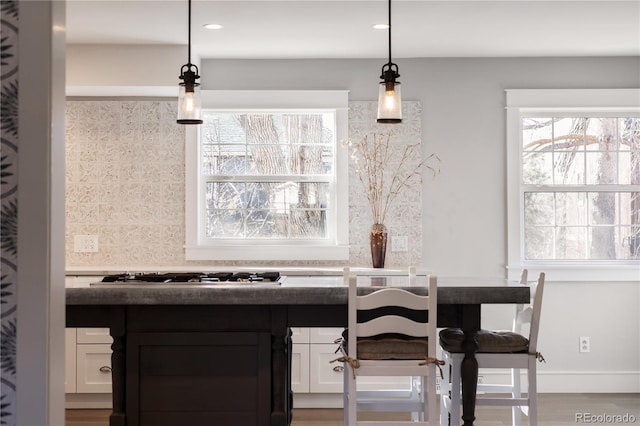 interior space featuring gas stovetop, decorative light fixtures, a wealth of natural light, and white cabinets