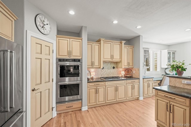 kitchen featuring stainless steel appliances, light brown cabinetry, backsplash, and light wood-type flooring