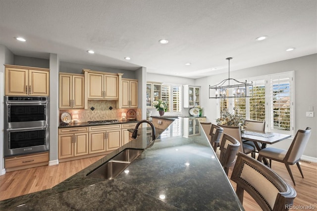 kitchen featuring sink, decorative light fixtures, stainless steel appliances, and dark stone counters