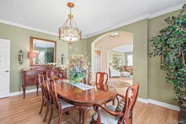 dining area with a notable chandelier, light hardwood / wood-style flooring, and ornamental molding