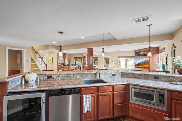 kitchen with stainless steel appliances, sink, pendant lighting, and beverage cooler