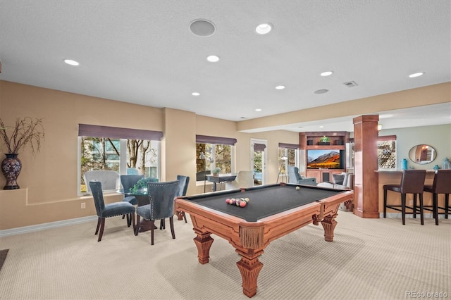 playroom featuring light carpet, decorative columns, a textured ceiling, and indoor bar