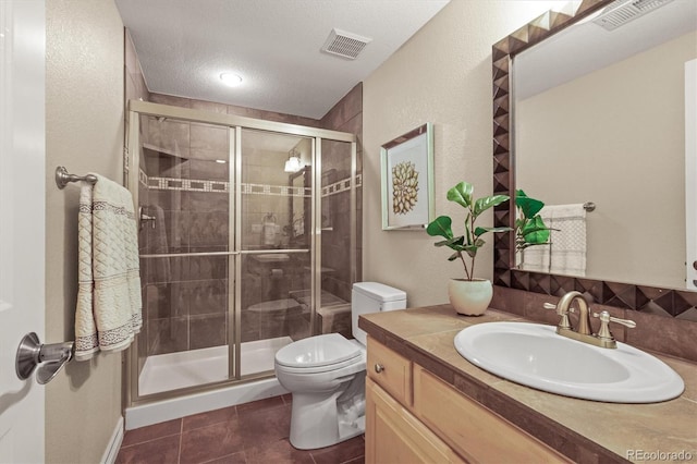 bathroom with vanity, toilet, a shower with door, tile patterned floors, and a textured ceiling