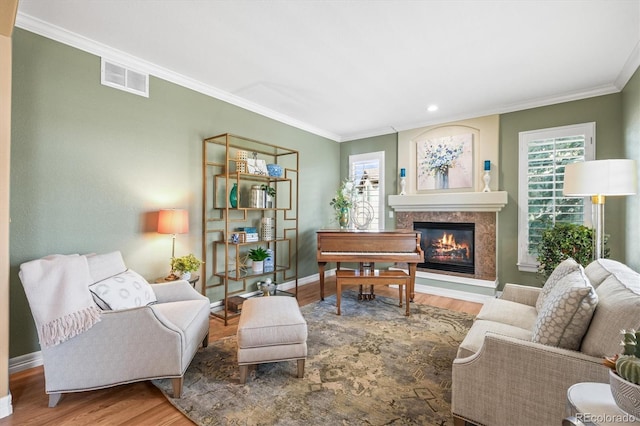 living room featuring a fireplace, visible vents, wood finished floors, and ornamental molding