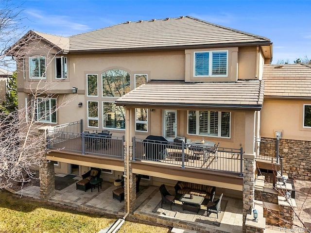 rear view of property with outdoor lounge area, a patio, and stucco siding