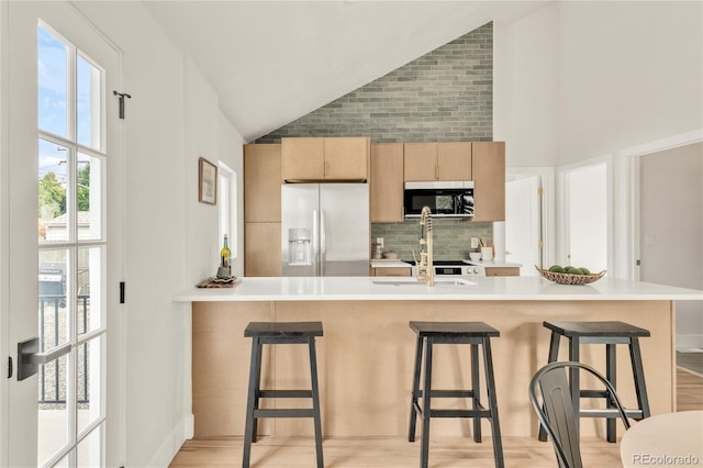 2600 S Downing St, Denver, CO 80210 - kitchen featuring white refrigerator with ice dispenser, stainless steel microwave, lofted ceiling, tasteful backsplash, and a breakfast bar area