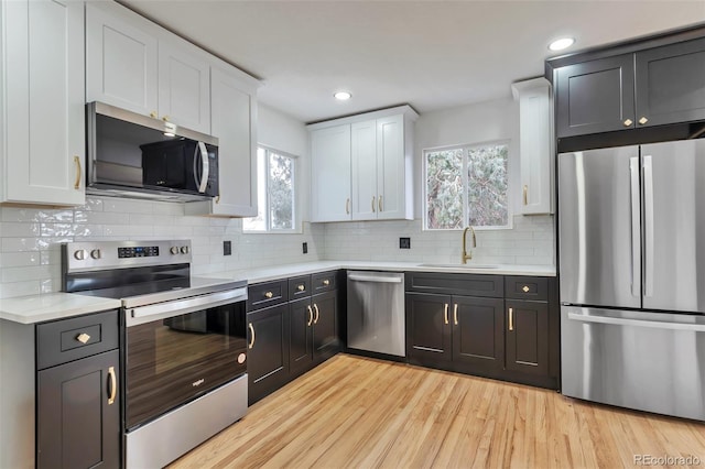 kitchen with tasteful backsplash, sink, white cabinets, and appliances with stainless steel finishes