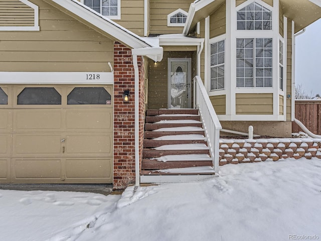 snow covered property entrance featuring a garage