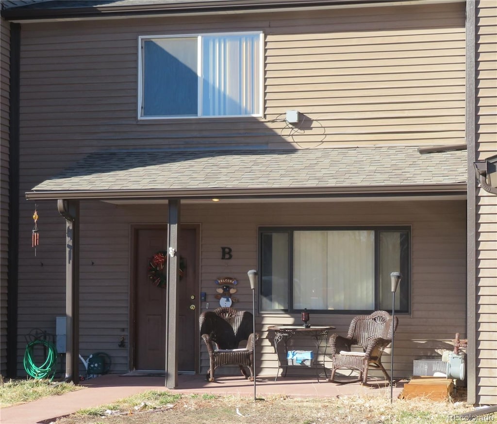 rear view of property with a porch and roof with shingles