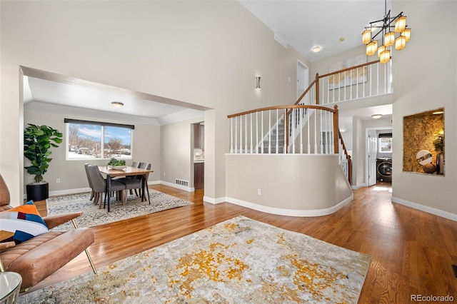 interior space with a notable chandelier, washer / dryer, a towering ceiling, and hardwood / wood-style flooring