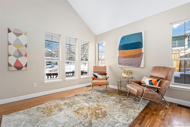 living area with high vaulted ceiling and hardwood / wood-style floors