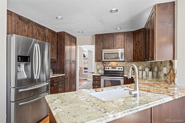 kitchen with kitchen peninsula, decorative backsplash, light stone counters, and stainless steel appliances