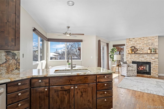 kitchen with a fireplace, light stone countertops, sink, and dark brown cabinetry