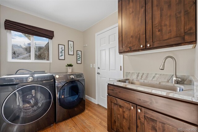 laundry area with cabinets, light hardwood / wood-style floors, independent washer and dryer, and sink