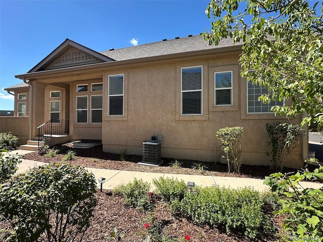 back of house with central air condition unit and stucco siding