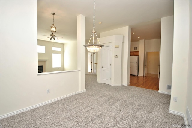 carpeted spare room featuring recessed lighting, a ceiling fan, visible vents, baseboards, and a glass covered fireplace