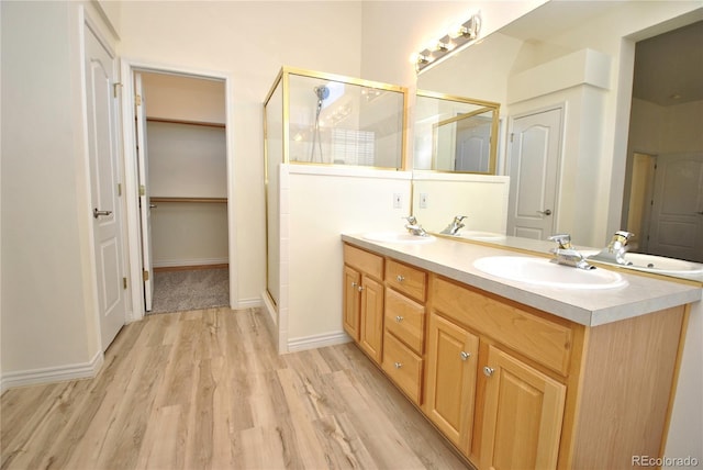 full bathroom featuring a stall shower, a sink, and wood finished floors